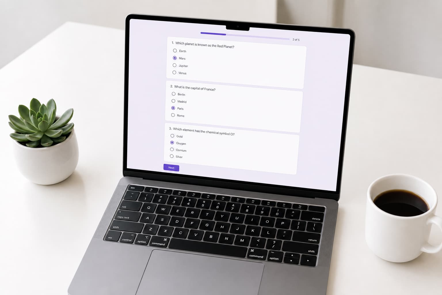Un ordinateur portable affichant un questionnaire de type Google Forms avec questions à choix multiples et une barre de progression, posé sur un bureau blanc propre avec une tasse de café et une petite plante grasse.